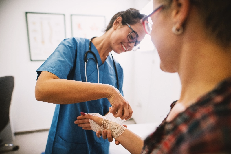 CNA wrapping a patient's hand with gauze